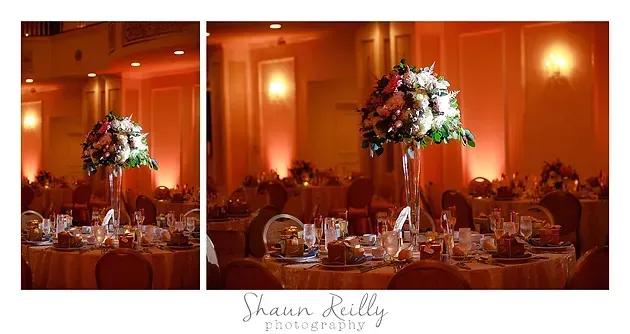 Warm orange wedding reception with floral centerpieces on round tables and candlelit decor
