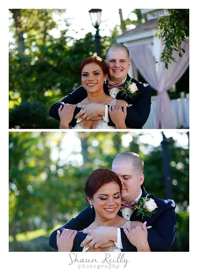 Couple embracing outdoors in a garden, smiling in wedding attire under soft sunlight.