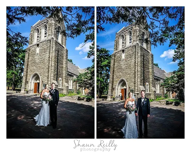 Wedding couple posing outside a stone church beneath blue sky and tree branches