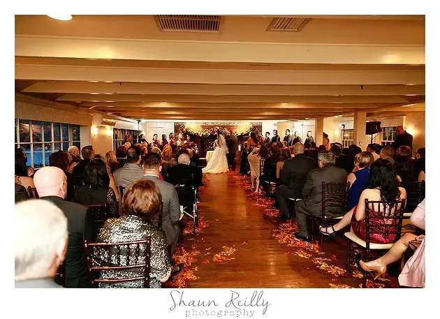 Banquet hall with guests seated along a red carpet aisle under warm lighting