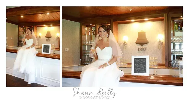 Bride in white gown posing at a bar, with warm wood paneling and framed artwork in the background