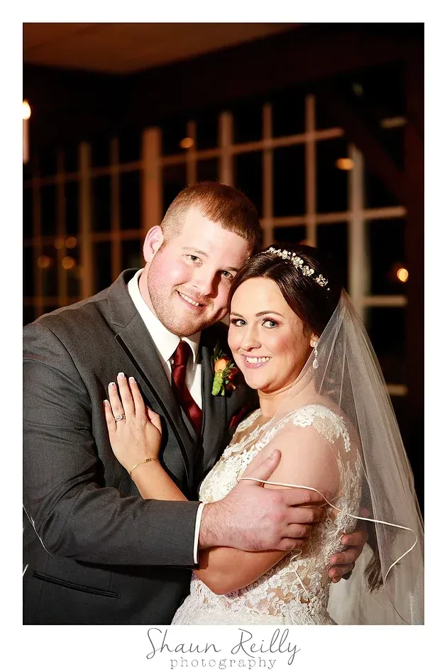 Bride and groom embracing and smiling in a formal portrait