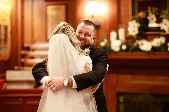 Bride and groom embracing in a warmly lit church during their wedding ceremony