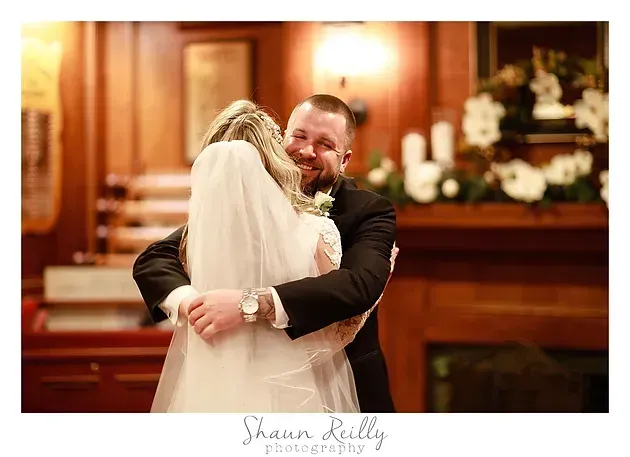 Bride and groom embracing in a warmly lit church sanctuary during their wedding ceremony