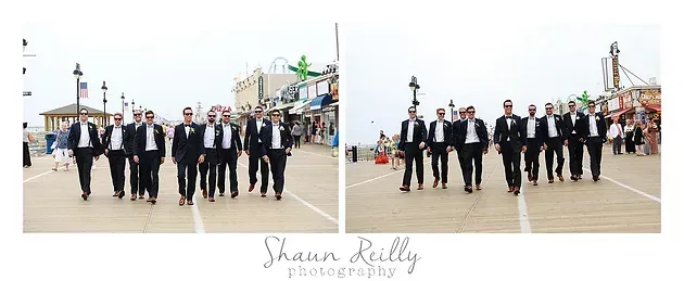 Group of people in black suits walking on a pier with ferris wheels in the background