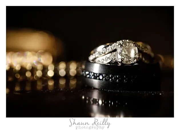 Diamond wedding rings on a dark reflective surface, with one ring in sharp focus