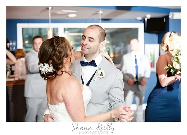 Bride and groom sharing a kiss at a wedding reception with guests in the background