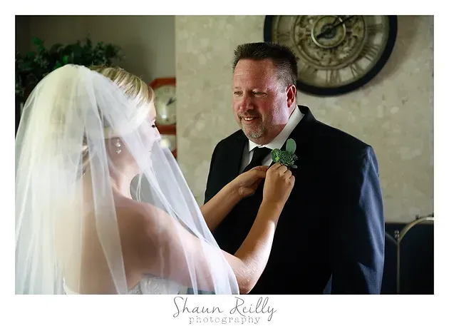 Bride adjusting groom's boutonniere during wedding ceremony