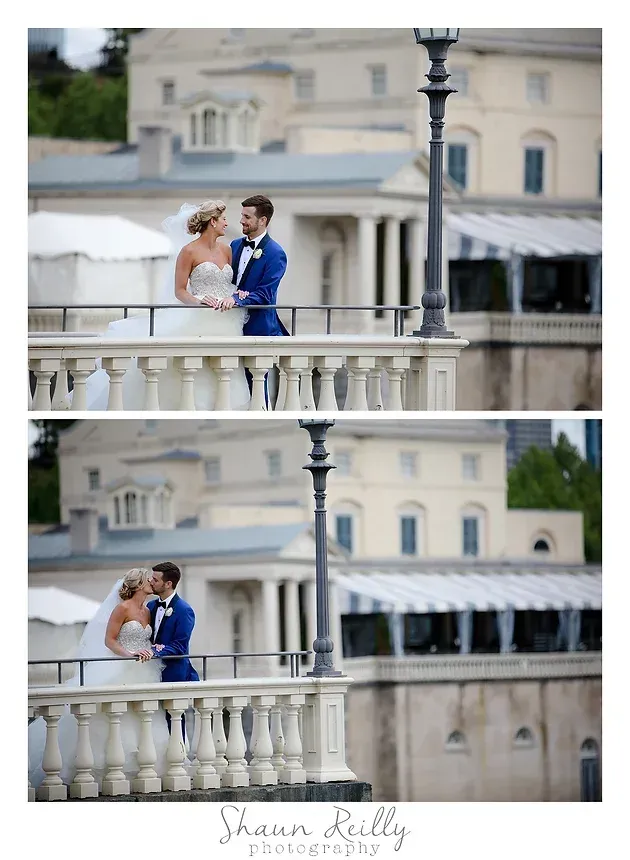 Couple embracing on a bridge, the man in a blue suit and the woman in a white dress.