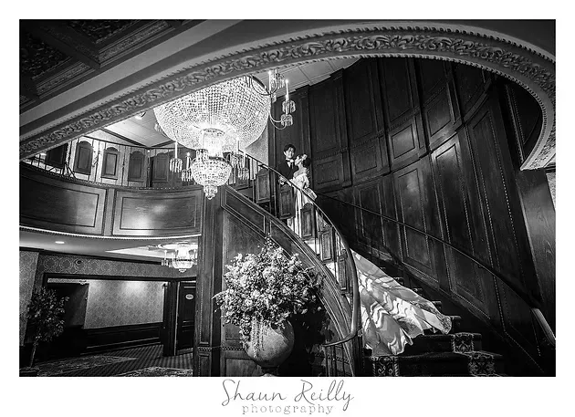 Grand staircase with chandelier and floral arrangements in an elegant interior