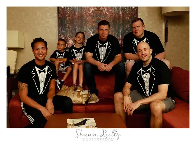 Five people in matching black shirts posed on a staircase in a home, smiling at the camera