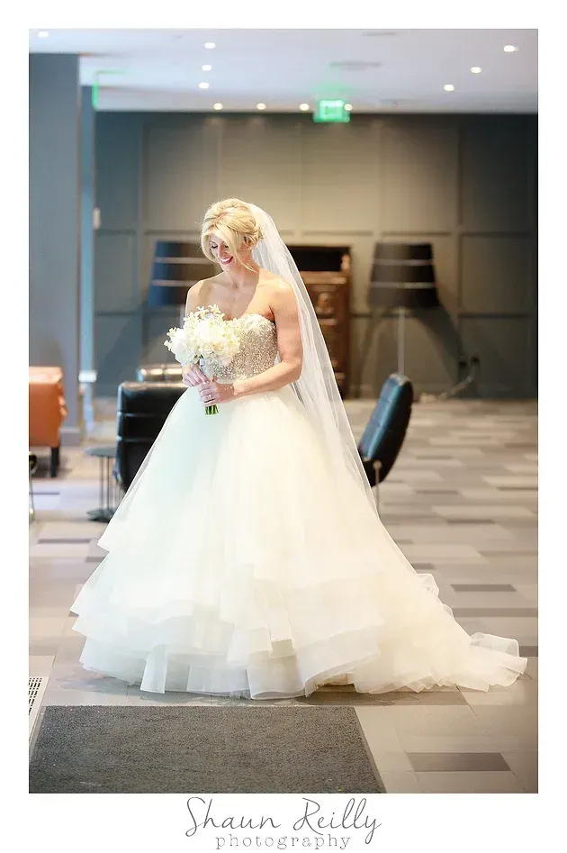 Bride in a white gown holding a bouquet in a modern indoor venue