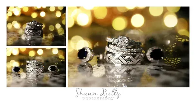 Three sparkling diamond rings on a reflective surface with warm gold bokeh lights behind them