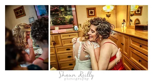 Two women embrace and smile in a warm, wood-paneled kitchen with soft lighting.