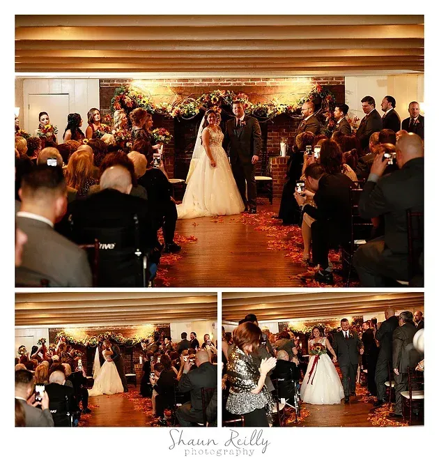 Wedding couple exchanging vows under floral arch in a warmly lit ceremony room, guests seated on both sides