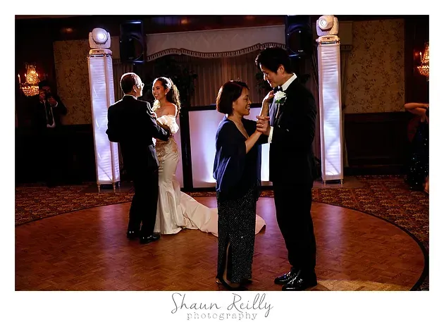 Two couples dancing in an elegant ballroom with warm lighting and columns