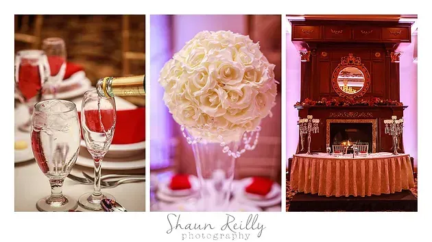 Elegant wedding reception decor with red table settings, white floral centerpiece, and ornate stage backdrop