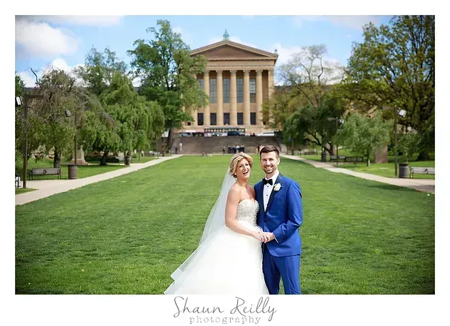 Bride and groom posing on a green lawn in front of a neoclassical building