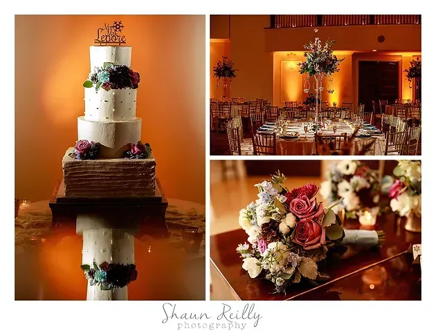 Elegant wedding cake and reception tables with warm amber lighting and floral centerpieces in a banquet hall