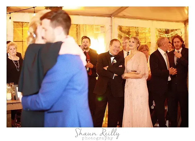 Guests dancing and chatting at a warmly lit indoor wedding reception.