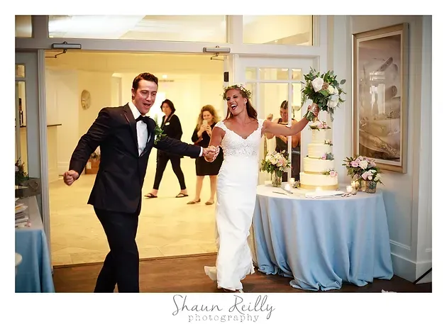 Bride and groom dancing at a wedding reception with floral decor and a cake table