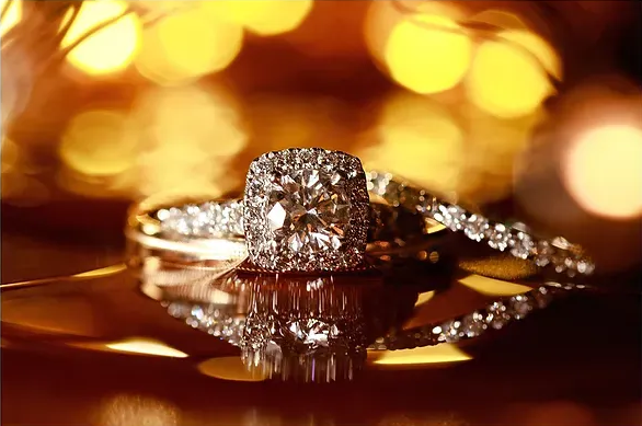 Diamond engagement ring on a reflective surface with warm golden lights in the background