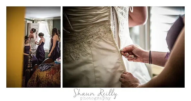 Bridal gown being zipped up as bride looks in mirror, with white dress details and helper at side