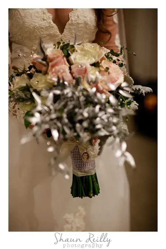 Bride holding a white and pink bridal bouquet with silver accents and green stems