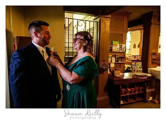 Couple smiling as she adjusts his tie in a warmly lit room with wood paneling