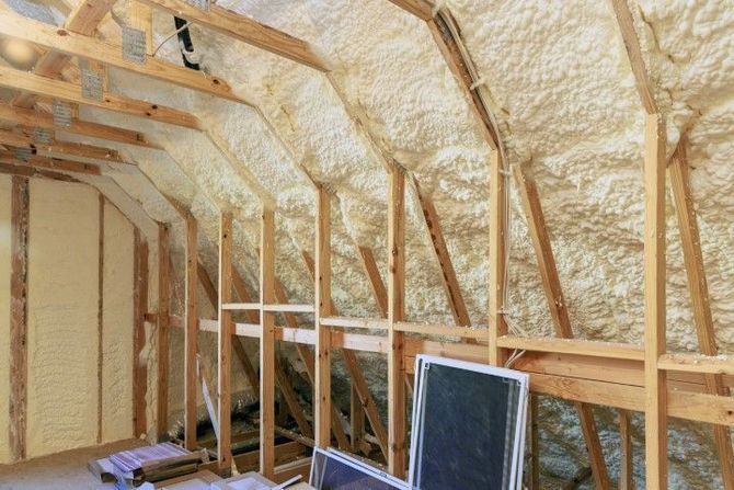 Insulated attic with exposed wooden framing and foam-covered walls under construction