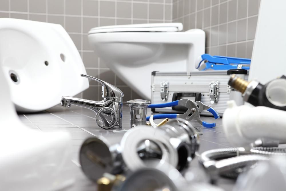 Bathroom With a Toilet, Sink, and Plumbing Tools on the Floor — Approved Plumbing Service in Winnellie, NT