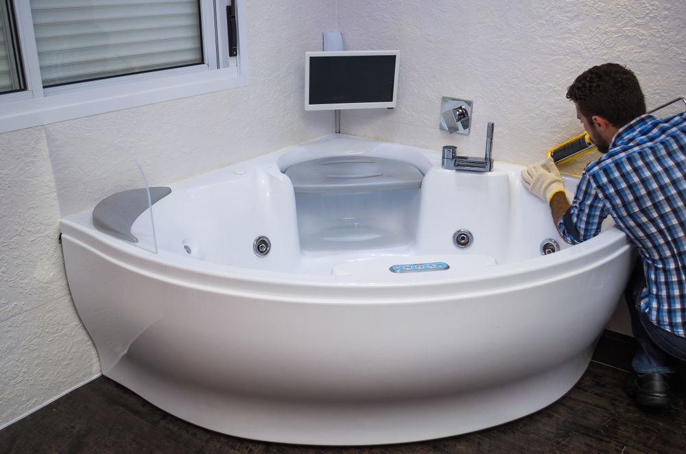 A Man is Fixing a Leak on Jacuzzi Tub in a Bathroom — Approved Plumbing Service in River Heads, QLD