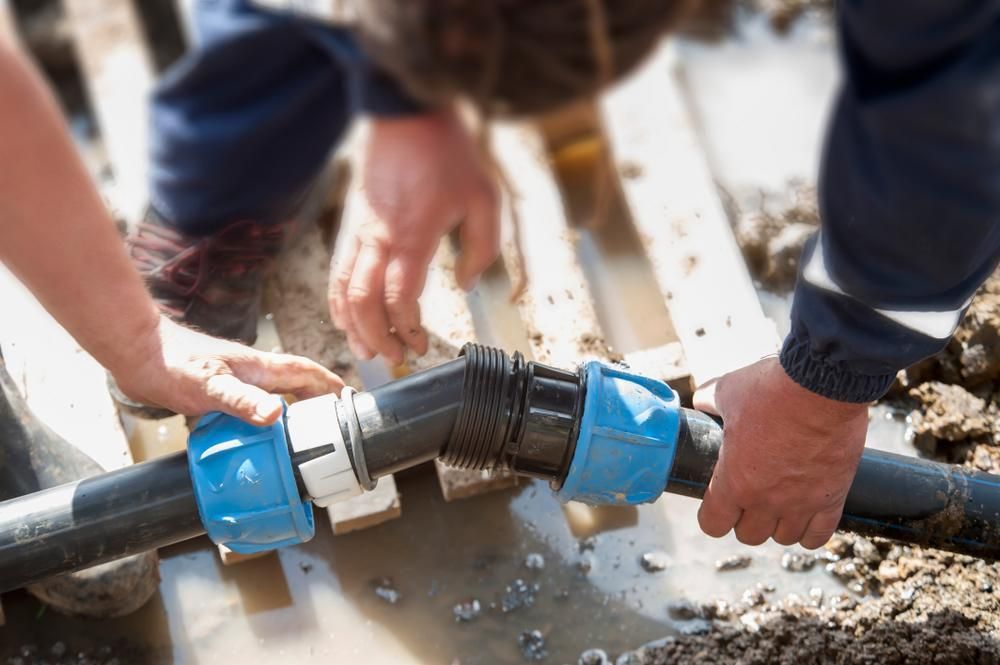 Man is Fixing a Pipe in a Puddle of Water — Approved Plumbing Service in Nightcliff, NT