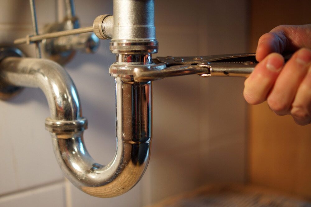 Man Fixing Sink Pipe with Wrench — Approved Plumbing Service in Burrum Heads, QLD