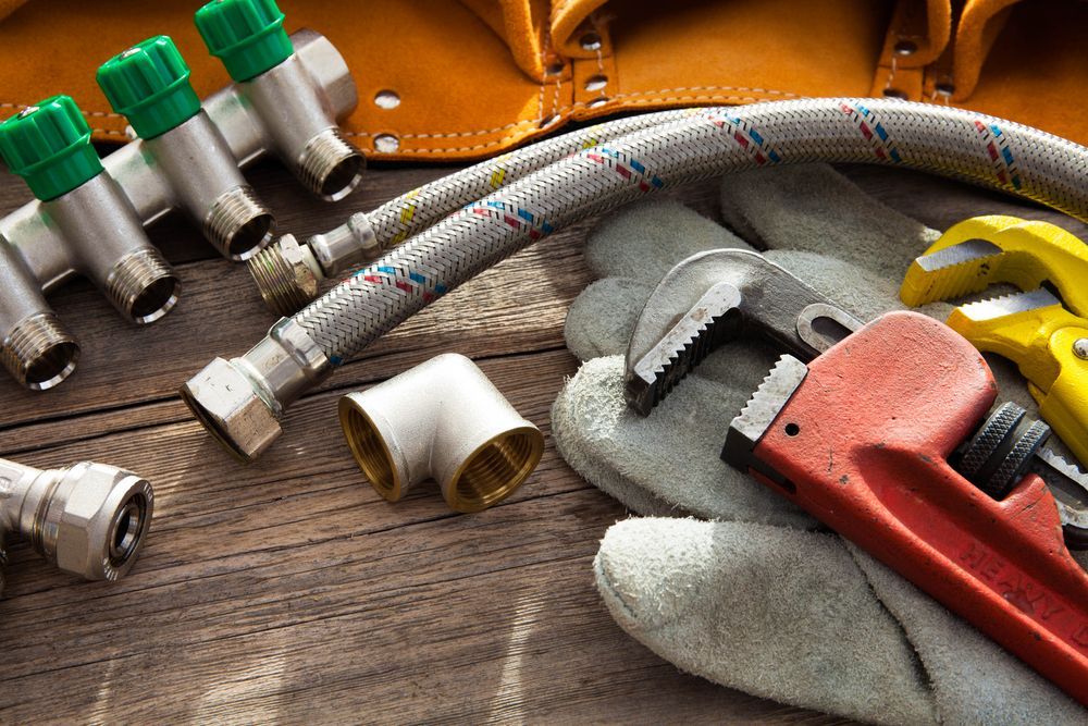Pair of Gloves , a Wrench , Pipes , and a Tool Bag — Approved Plumbing Service in Berrimah, NT