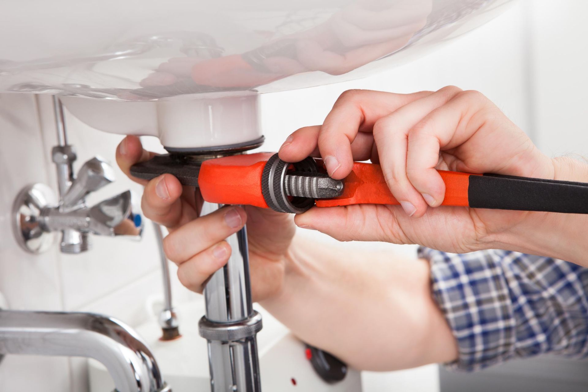 A Plumber Is Fixing A Sink With A Wrench — Approved Plumbing Service in Hervey Bay, QLD