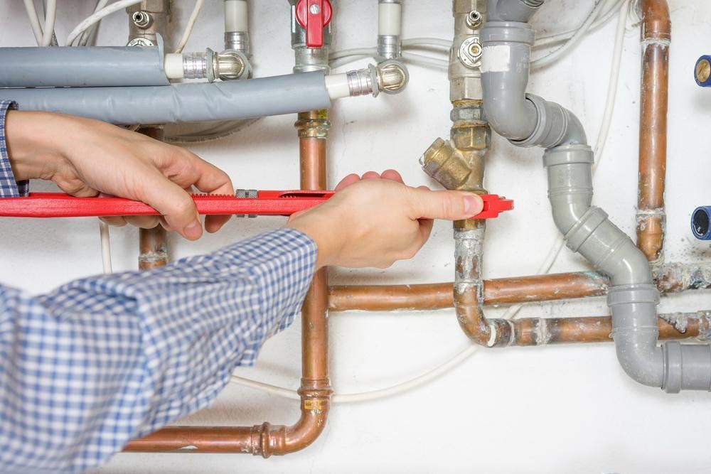 Plumber is Fixing a Pipe With a Wrench — Approved Plumbing Service in Woolner, NT