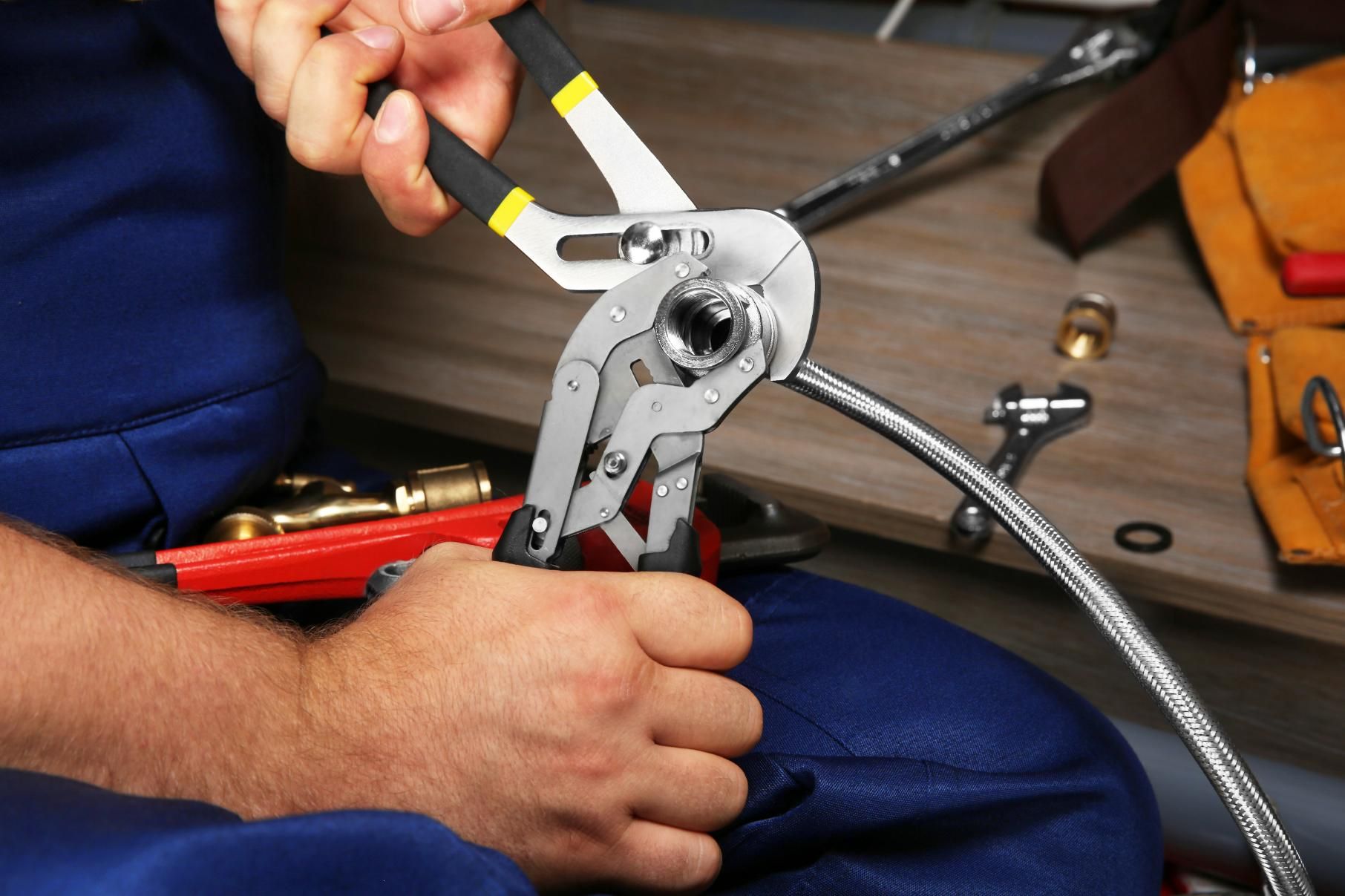 Plumber is Working on a Hose With a Wrench and Pliers — Approved Plumbing Service in Nightcliff, NT