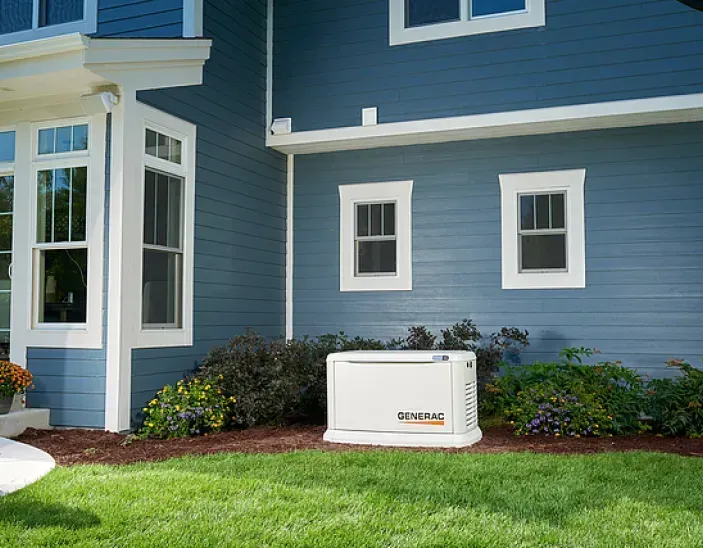 A blue house with a generator in the backyard.