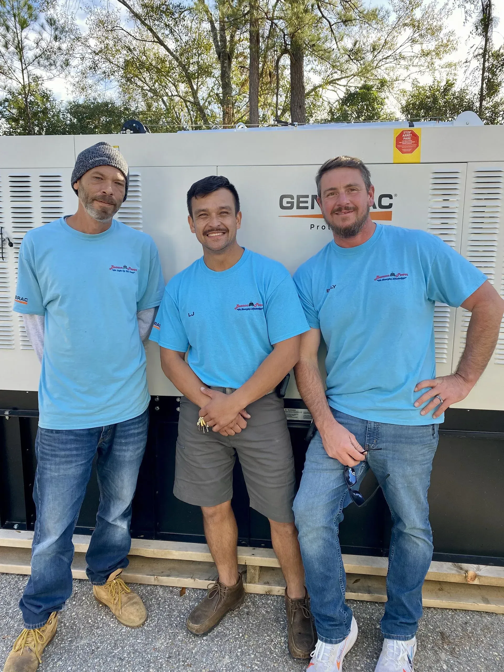 Three men are posing for a picture in front of a generator.