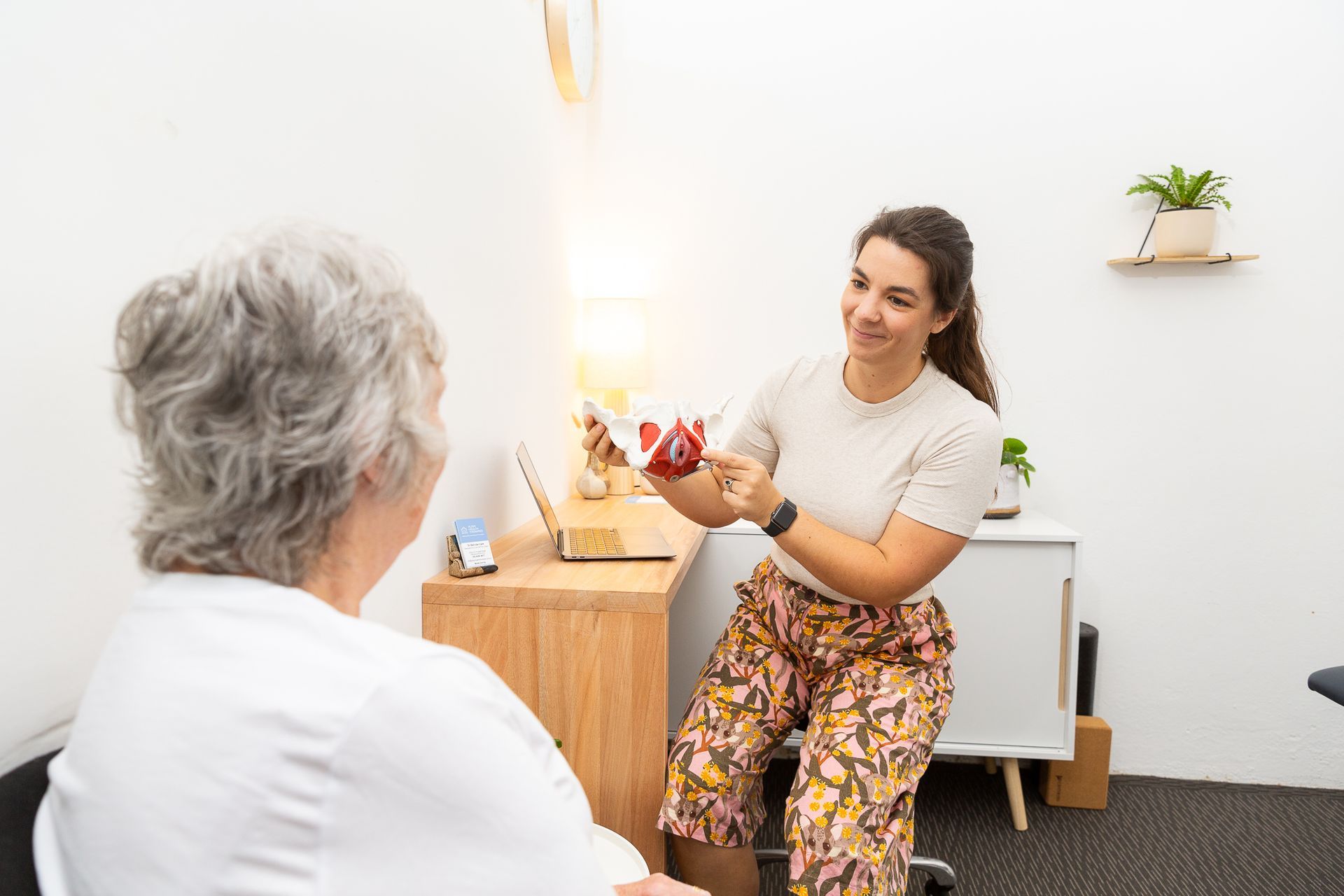 A woman sitting at a desk talking to another woman — Align Health Therapies in Woonona, NSW