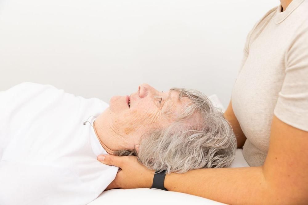 An Elderly Woman is Laying on a Bed Getting a Massage From a Woman — Align Health Therapies in Woonona, NSW
