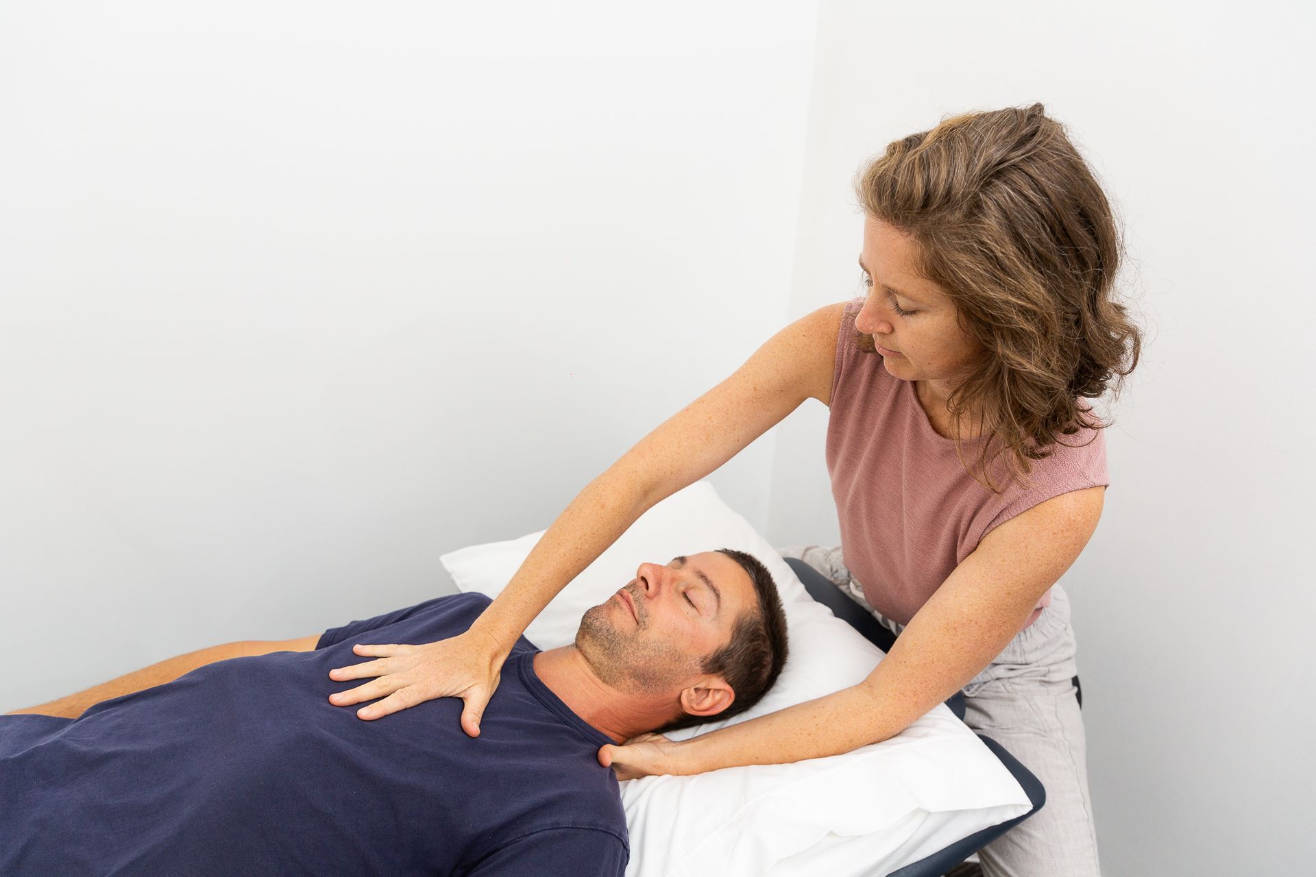 A woman is giving a man a massage while he is laying on a bed — Align Health Therapies in Woonona, NSW