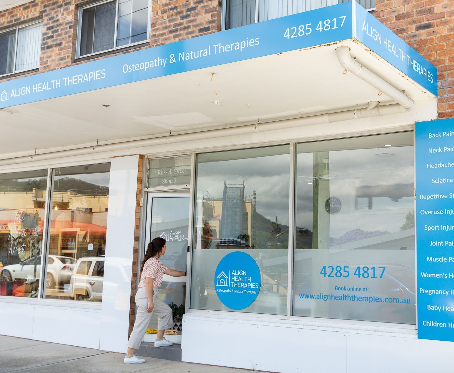 A woman is standing in the doorway of a building — Align Health Therapies in Woonona, NSW