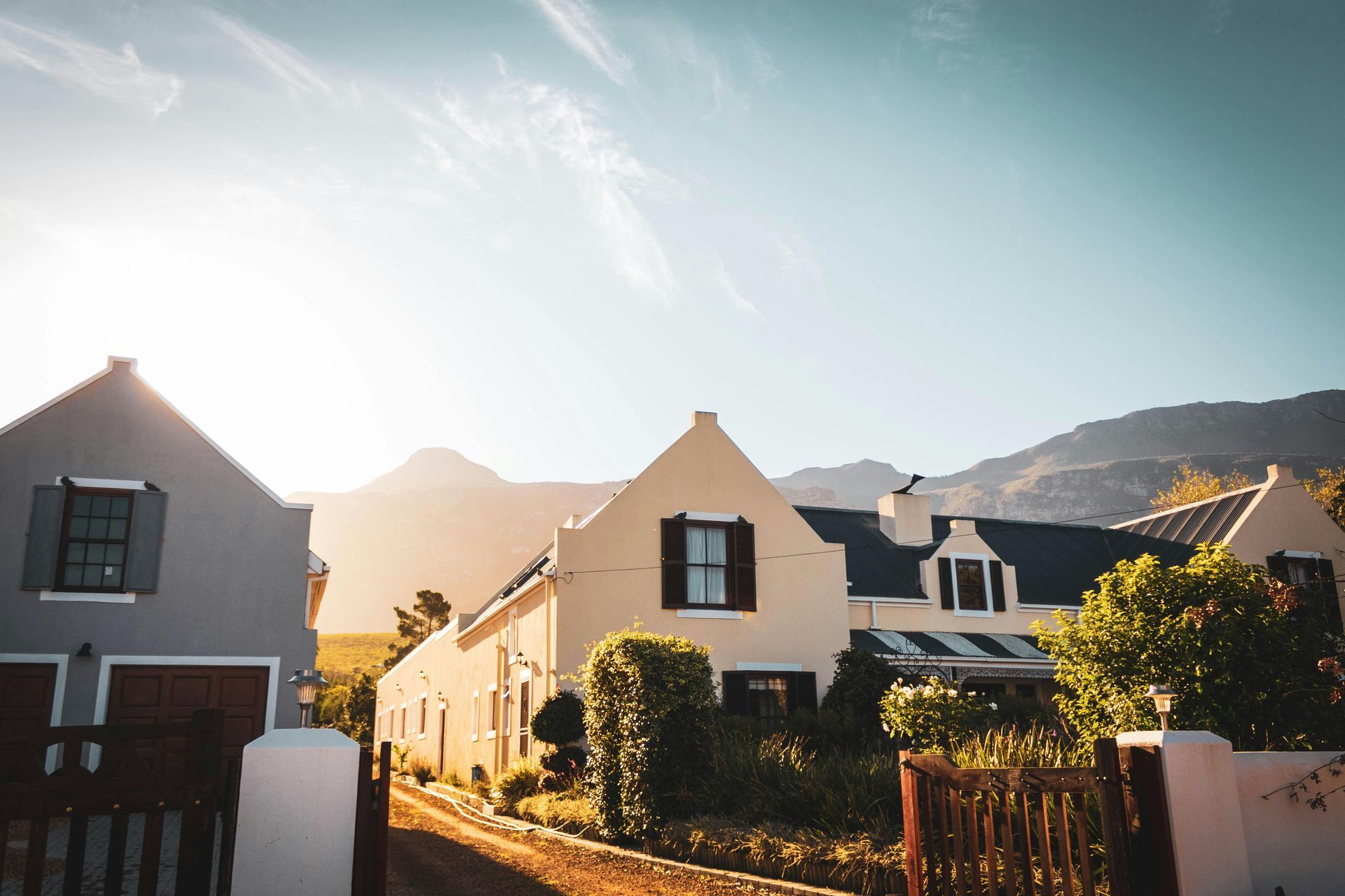 A row of houses sitting next to each other on a dirt road with mountains in the background.