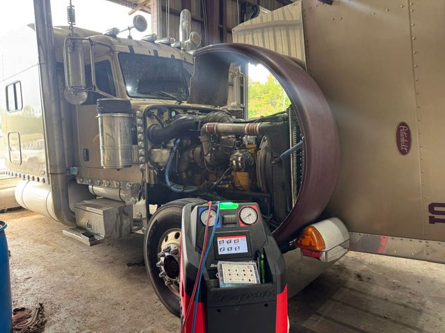 Semi truck with open hood being jump-started by a portable battery pack in a garage | Sellers Wrecker & Repair