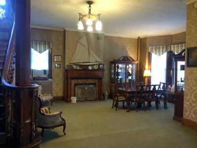 A room with ornate wood details, a fireplace with a sailboat model, and a dining table.