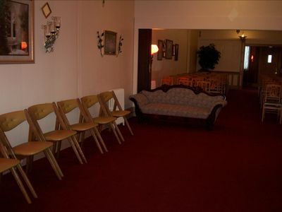 Empty funeral home viewing room with red carpet, chairs, and a couch.