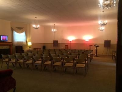 Interior of a room with rows of chairs facing a stage with lights.