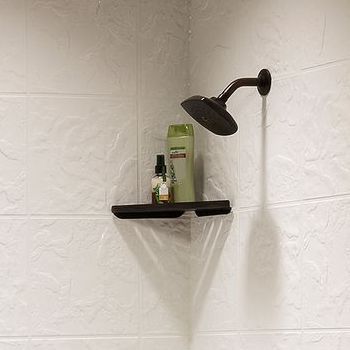 Shower head and shelf with toiletries on white tile wall.